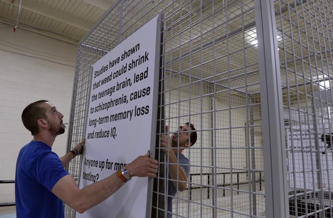 Crew members Andrew Willey, left, and Brian Houchin with Proctor Productions in Denver finish assembling large cages on Aug. 8, part of an advertising campaign by the state through Sukle Advertising designed to keep youths from using marijuana. (Kathryn Scott Osler, The Denver Post)