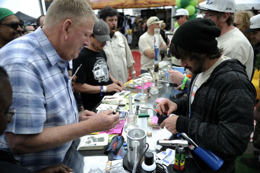 Chris Bagley, left, loads up a dab for a client at the Gaia booth during the Cannabis Cup in Denver on April 19, 2014. Gaia, now known by its new name Mindful, terminated its relationship with ad agency Cannabrand recently after the marketing company's executives were quoted somewhat controversially in a New York Times story. (Seth McConnell, The Denver Post)