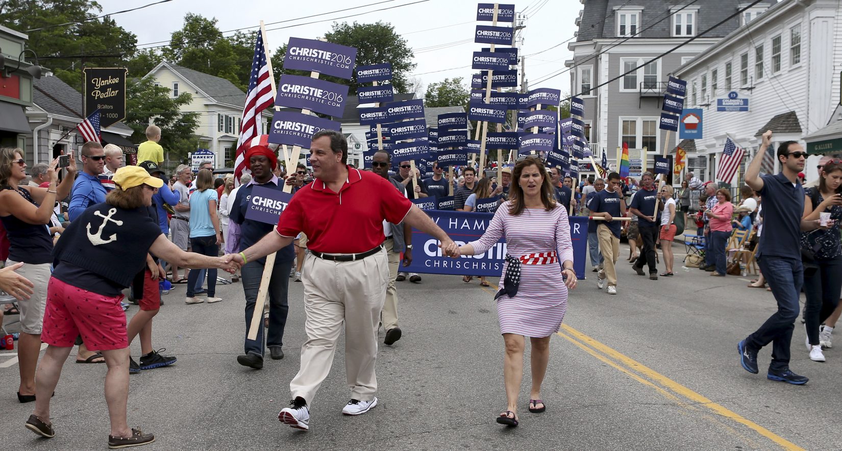 Republican presidential candidate New Jersey Gov. Chris Christie reaches out to shake hands as he and his wife wife Mary Pat walk through downtown Wolfeboro, N.H., during its Fourth of July parade. (Mary Schwalm, AP)