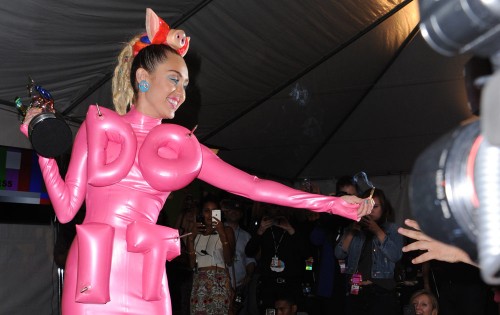 Miley Cyrus passes a lit joint to a photographer in the press room at the MTV Video Music Awards at the Microsoft Theater on Sunday, Aug. 30, 2015, in Los Angeles. (Richard Shotwell, Invision/Associated Press)