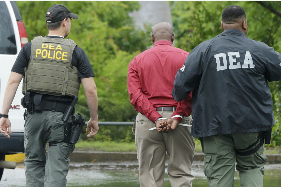 An unidentified man, center, is escorted from a medical clinic in Little Rock, Ark., by Drug Enforcement Administration officers on May 20, 2015. Early-morning raids in Arkansas, Alabama, Louisiana and Mississippi were the final stage of an operation launched last summer by the DEA's drug diversion unit, a senior DEA official said. (Danny Johnston, AP)
