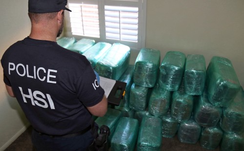 An investigator looks over bales of marijuana stored in the room of a newly-built house in Calexico., Calif., on March 23, 2016. The house is the terminus of a cross-border tunnel that runs the length of four football fields to a restaurant in Mexicali, Mexico. (U.S. Immigration and Customs Enforcement via AP) 