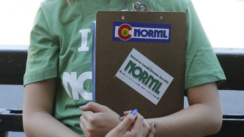 In this June 11, 2016 photo, a marijuana reform advocate with the group NORML holds a clipboard while waiting for passersby to sign a petition to get a pot club initiative on the ballot in the next election, in Denver. (AP Photo/Brennan Linsley)