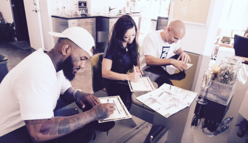 Rapper The Game, left, and Darice Smolenski, center, sign paperwork making The Game co-owner of The Reserve medical marijuana dispensary in Santa Ana, California. (Courtesy of The Reserve)