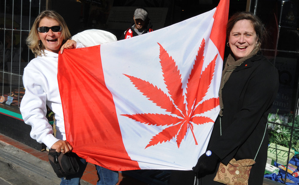 Two women hold Canada marijuana leaf flag